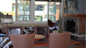 Una sala de estar con muebles de mimbre, una chimenea y un televisor montado en la pared.