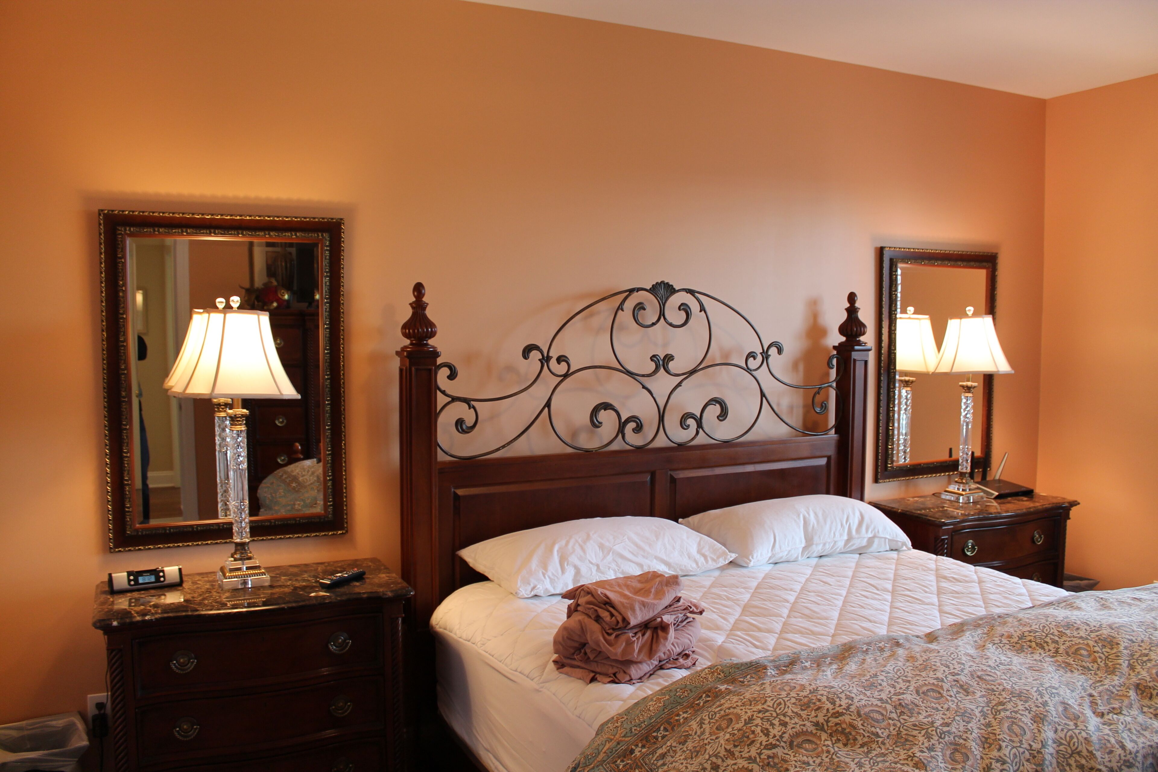 A hotel room with a bed, two nightstands with lamps, a dresser, and two wall mirrors.