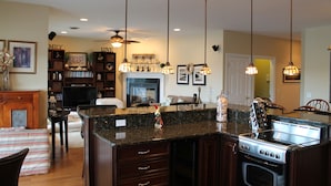 A spacious kitchen with granite countertops, a stainless steel stove, and pendant lighting.