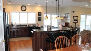 A kitchen with a central island, wooden chairs, and pendant lighting.