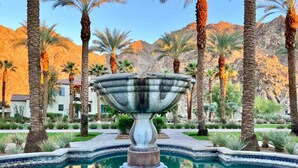 A pool with a central fountain, surrounded by palm trees and a mountainous backdrop. - La Villa #1 * Townhouse * 12 Pools *WoW Views (La Quinta)