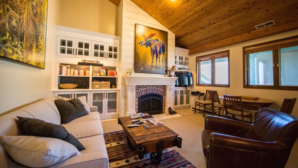 A cozy living room with a fireplace, a sofa, a coffee table, and a dining area.