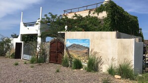 Un edifici amb façana de formigó, una porta de fusta i un quadre d'un paisatge.
