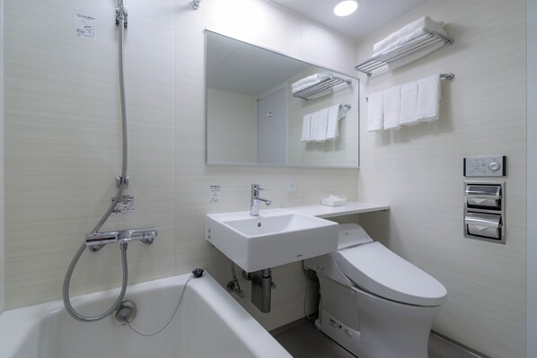 A modern bathroom with a bathtub, a sink, a toilet, a mirror, and a towel rack.
