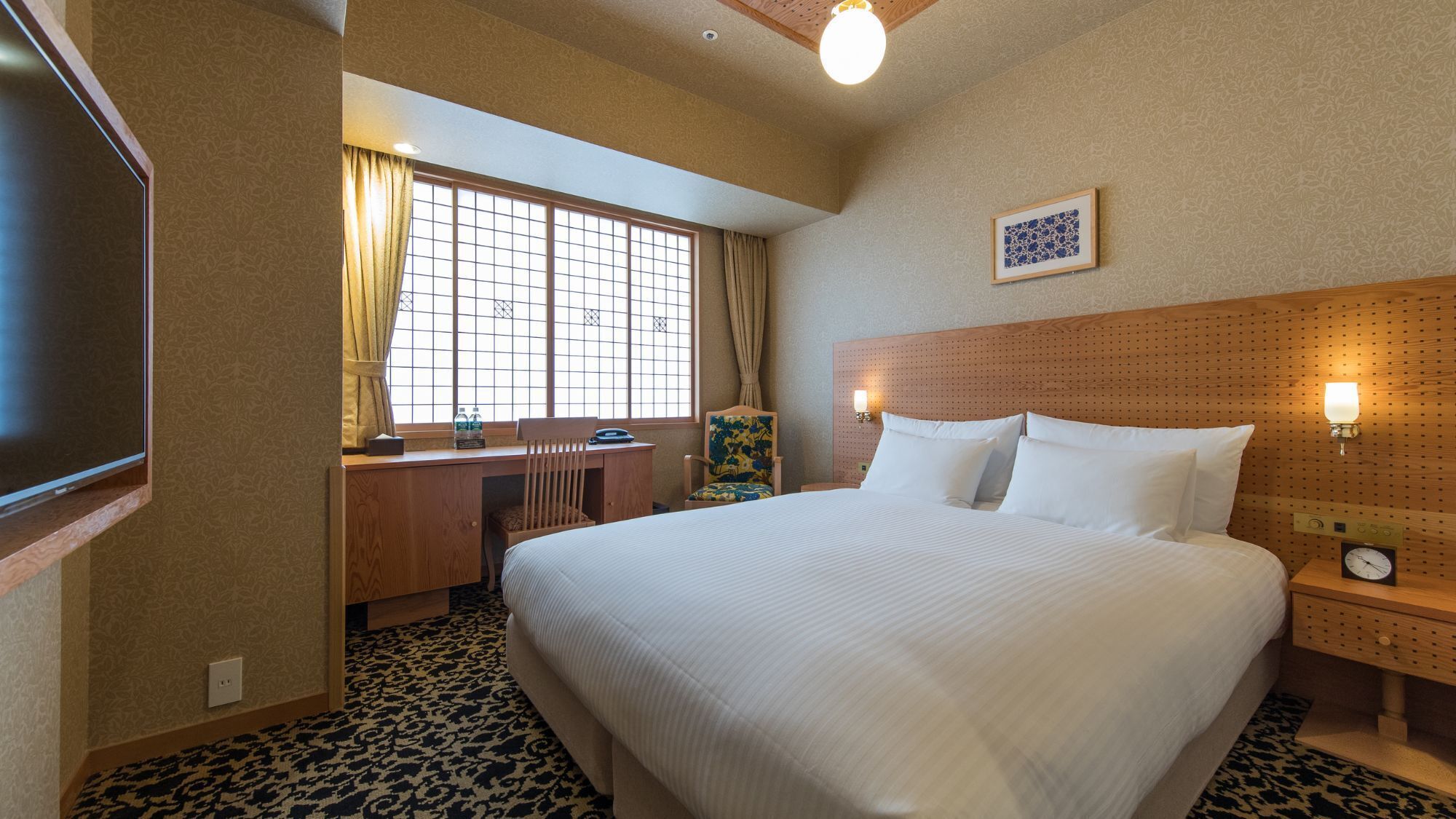 Une chambre d’hôtel équipée d’un lit, d’un bureau, d’une chaise et d’un téléviseur.