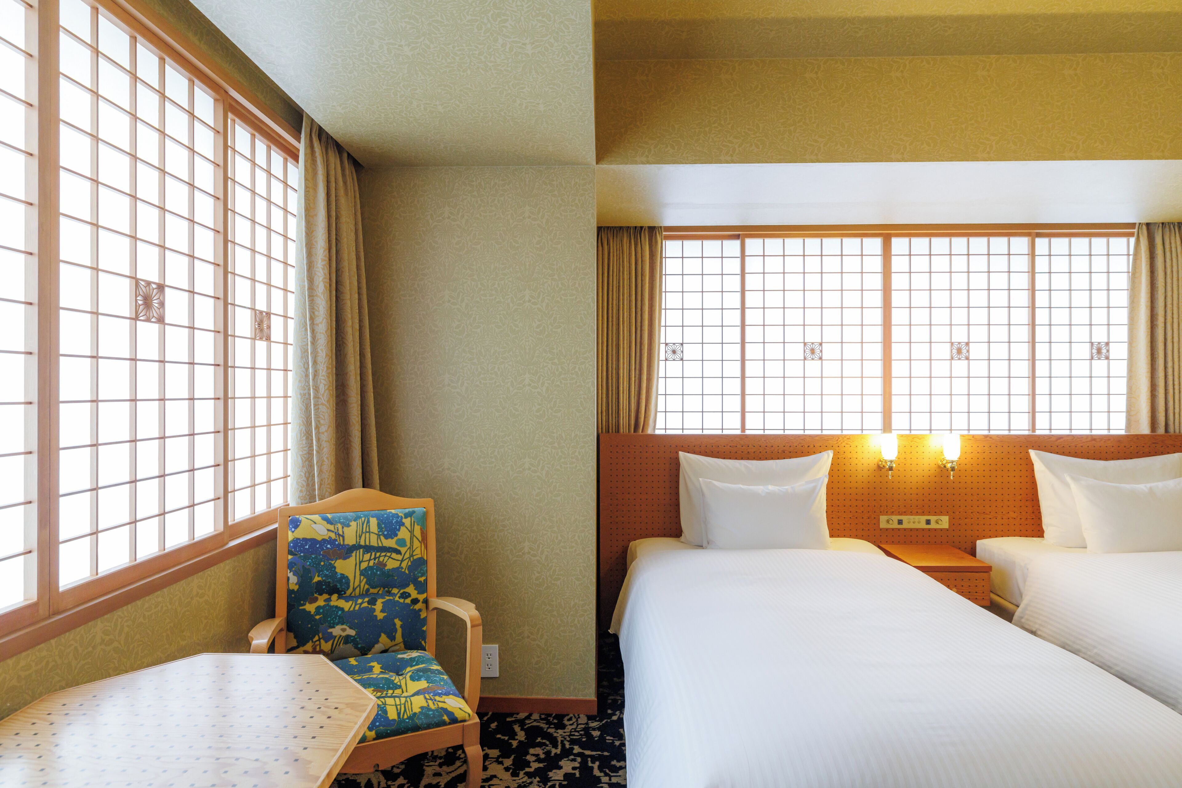 A hotel room with a bed, a chair, a table, and a window with a view.