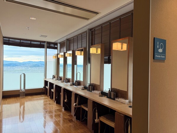 A row of sinks with mirrors, a sign for the powder room, and a view of the city and mountains through large windows. - JR KYUSHU HOTEL Blossom Oita (Oita)