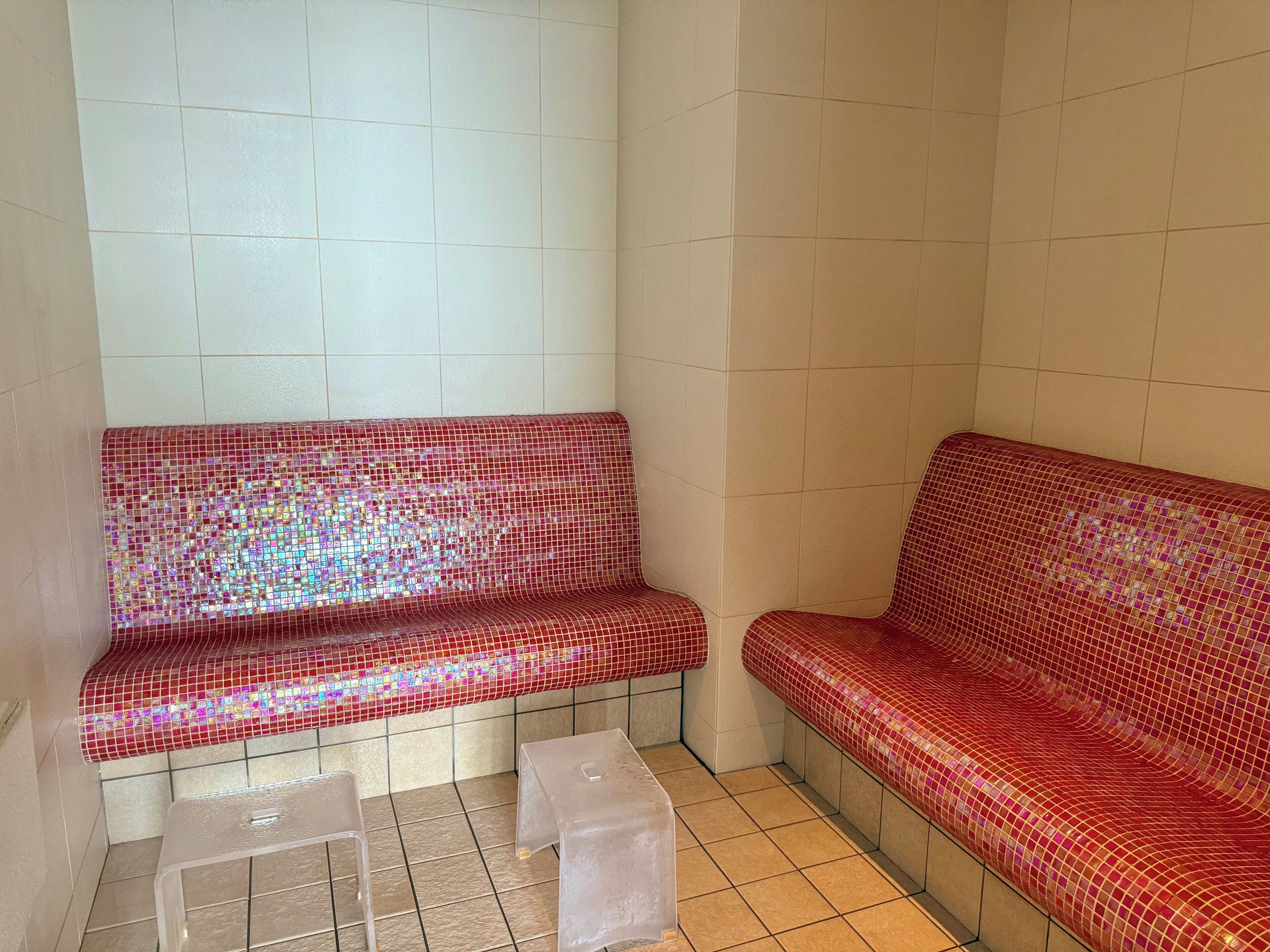 A room with two red mosaic benches and a small table.