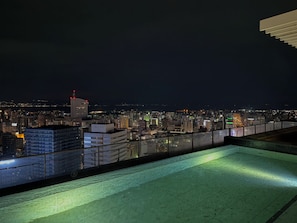 Eine Dachterrasse mit Blick auf die beleuchtete Stadt bei Nacht.