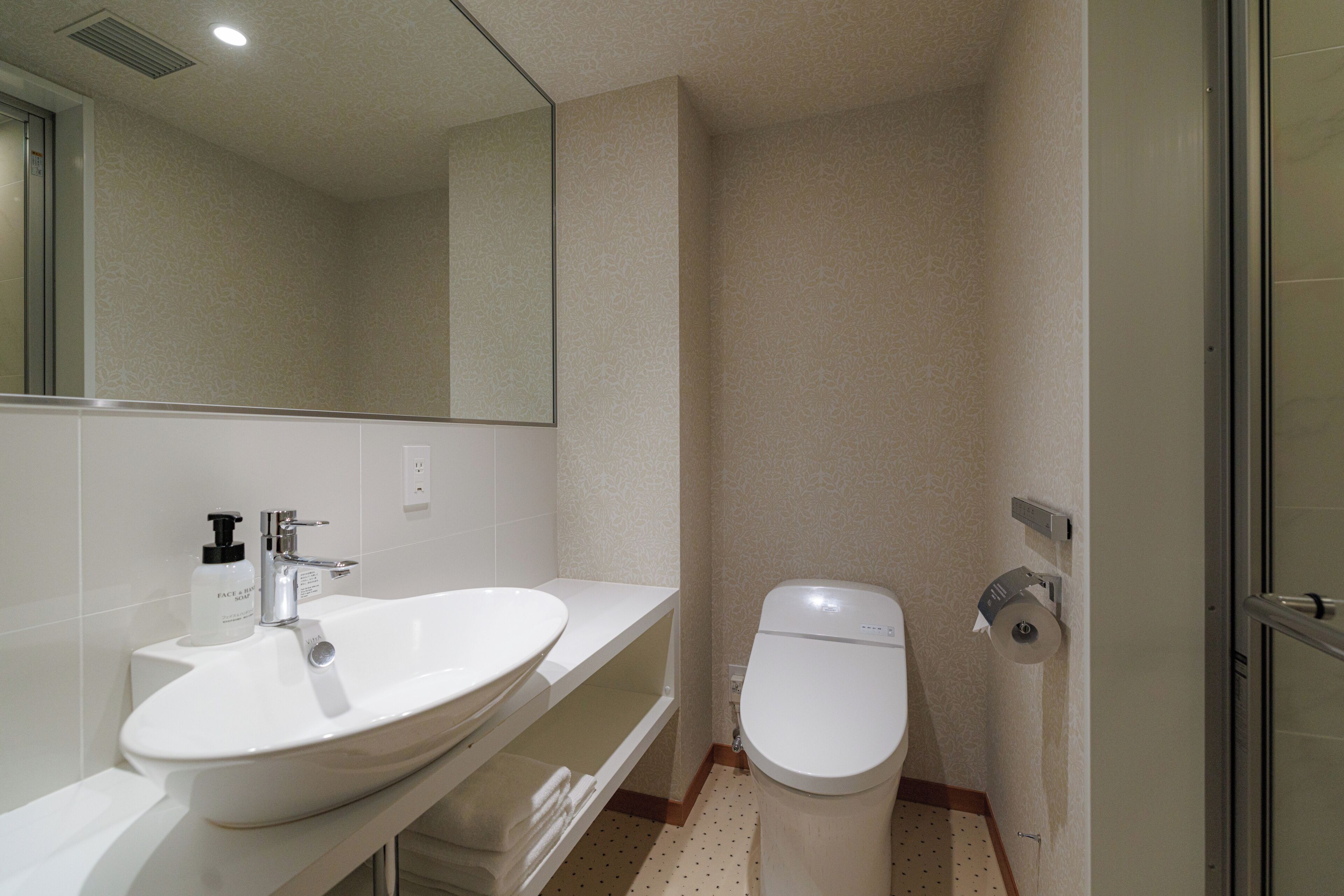 A bathroom with a white sink, a toilet, and a mirror.