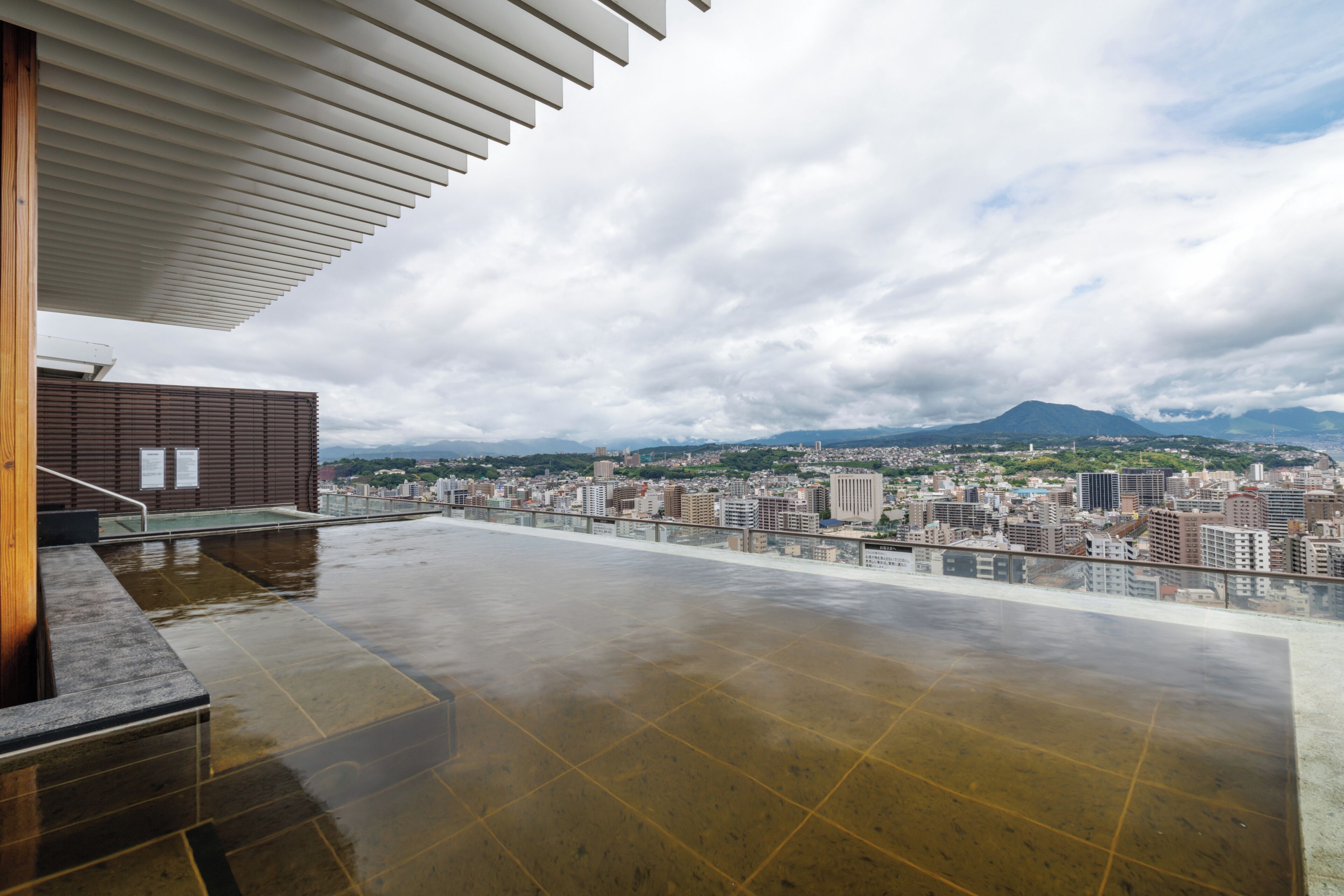 A rooftop terrace with a view of a cityscape and mountains.