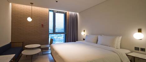 A modern hotel room with a large bed, a small round table, and a seating area.