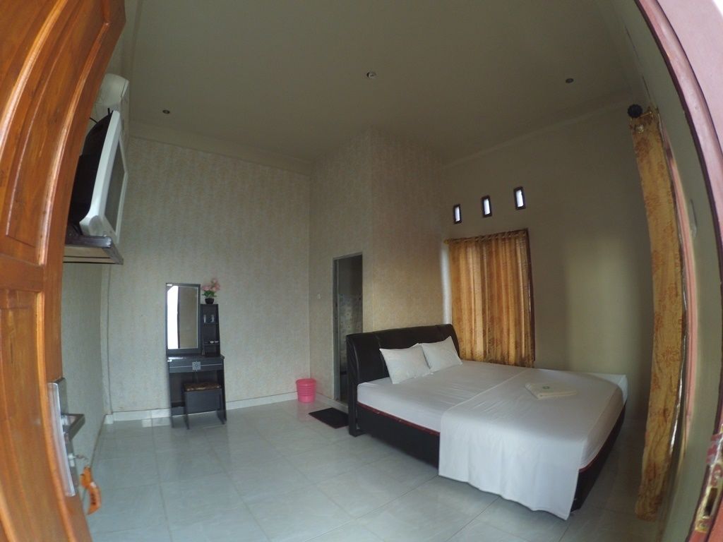 A bedroom with a large bed, a dresser, a mirror, and a window with curtains.
