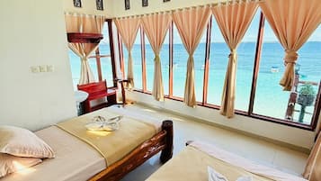 Ein Hotelzimmer mit zwei Betten, einem kleinen Tisch und Meerblick.