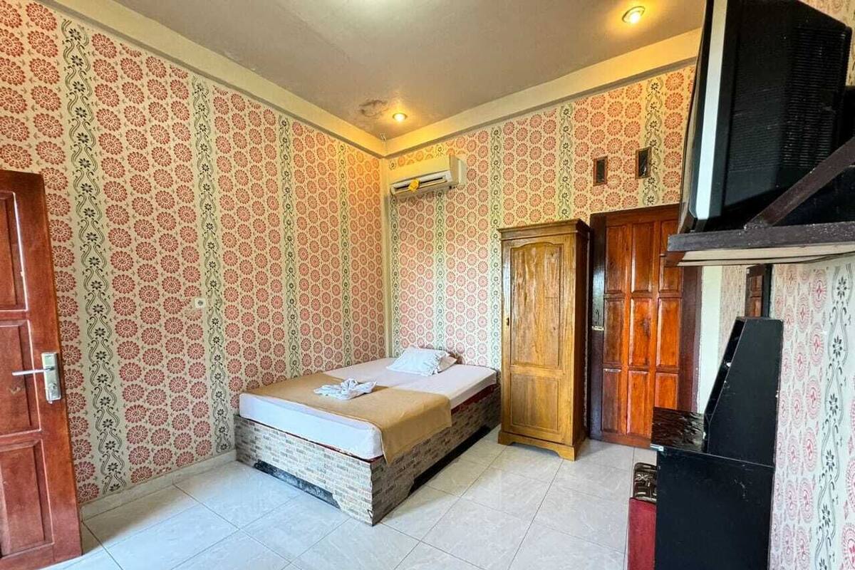 Un dormitorio con cama, armario y televisor.
