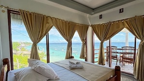 Una habitación con una cama grande, vista al mar y un balcón con baranda de madera.