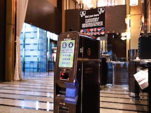 A currency exchange machine with multiple currency options and a sign indicating a money exchange service. - APA Hotel Kanda Ekimae (Tokyo)