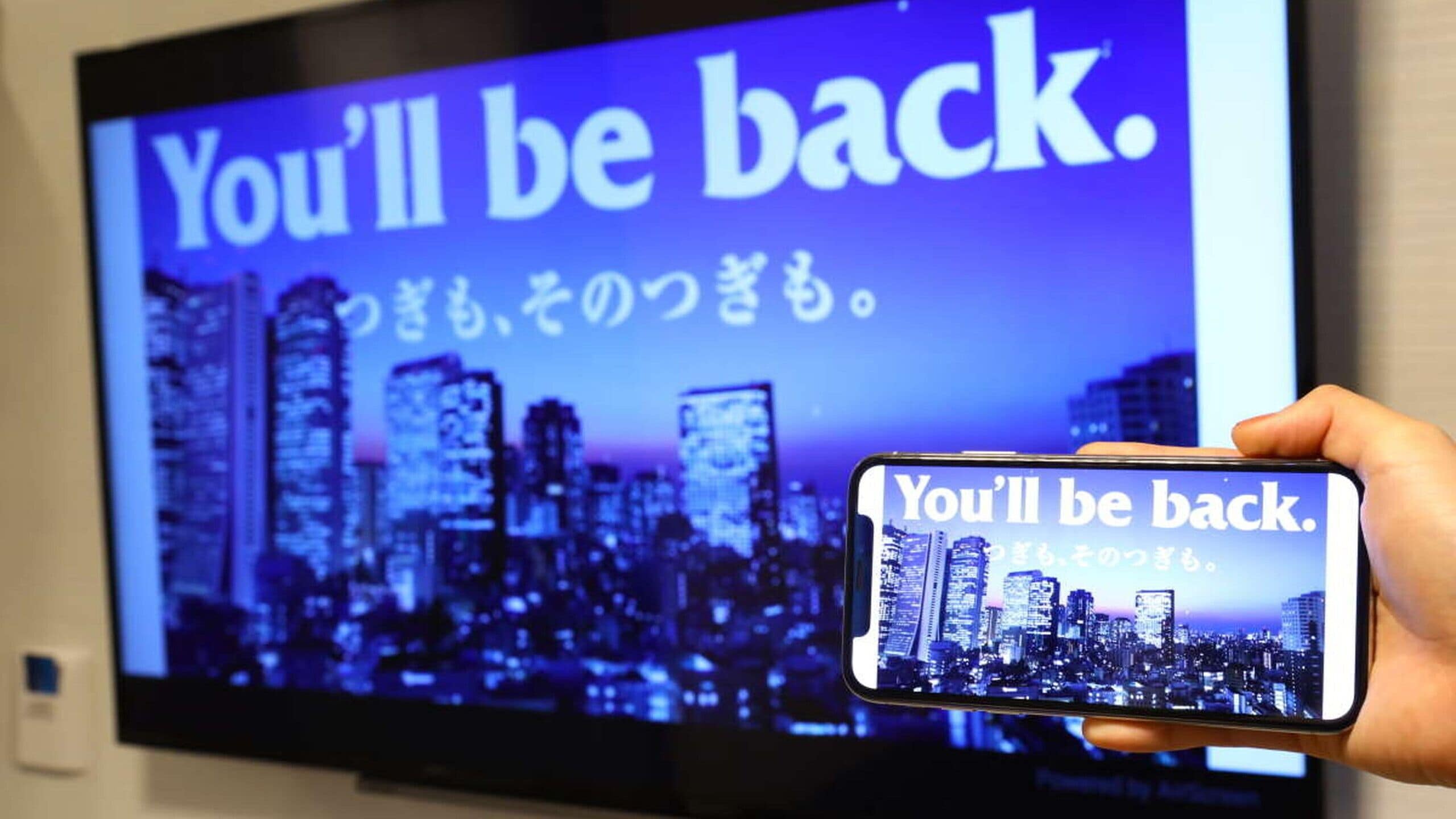 A smartphone displaying 'You'll be back.' with a cityscape background.