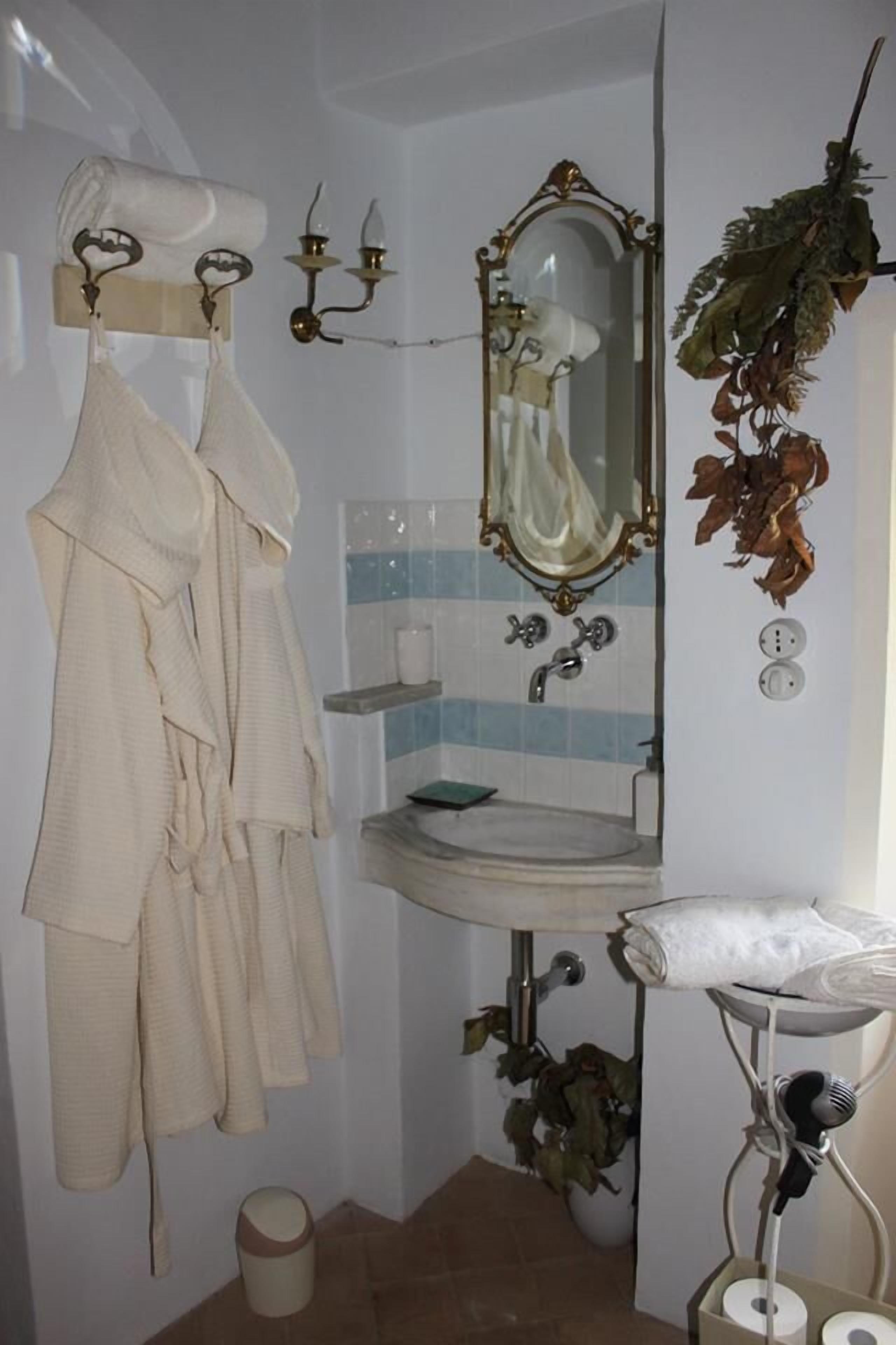 A bathroom with a sink, mirror, towel rack, and decorative plants.
