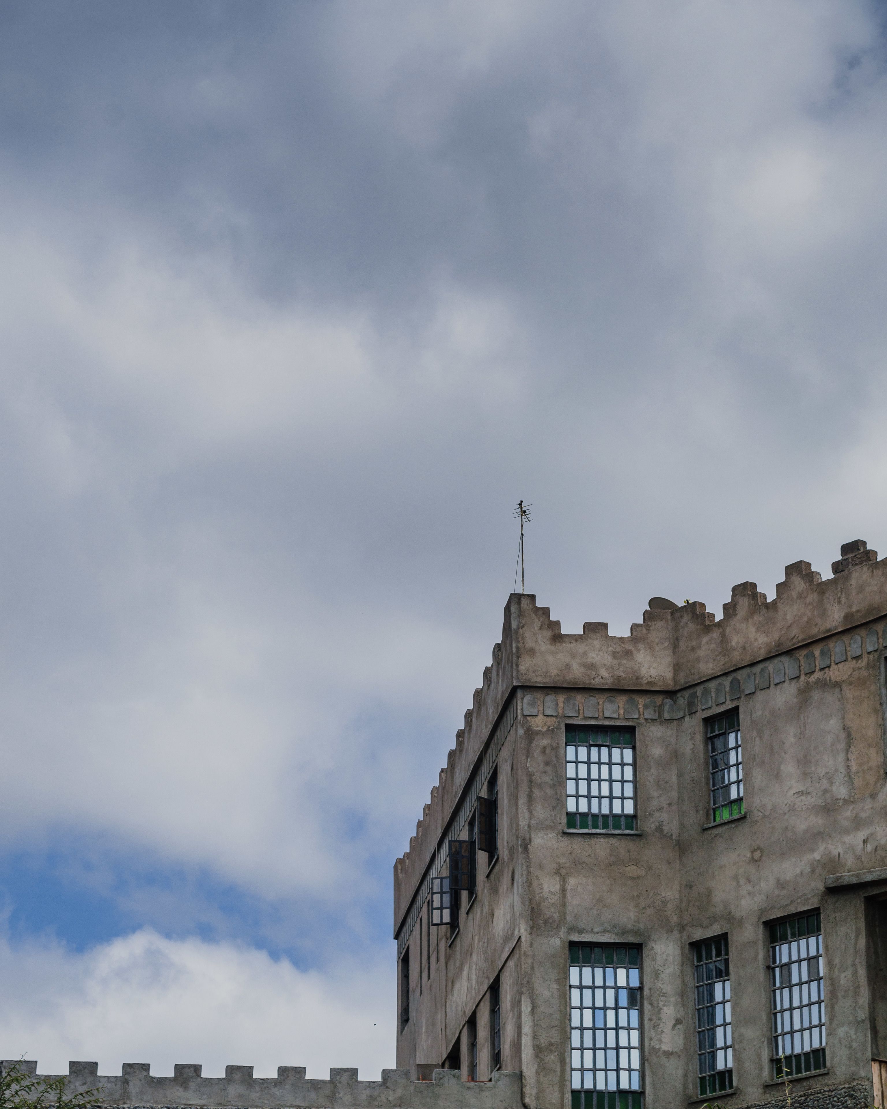 Un bâtiment à la façade évoquant un château, doté de nombreuses fenêtres et surmonté d’un girouette.