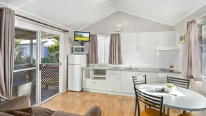 Eine moderne Küche mit weißen Schränken, einem Esstisch mit Stühlen, einem Fernseher und einem Kühlschrank.