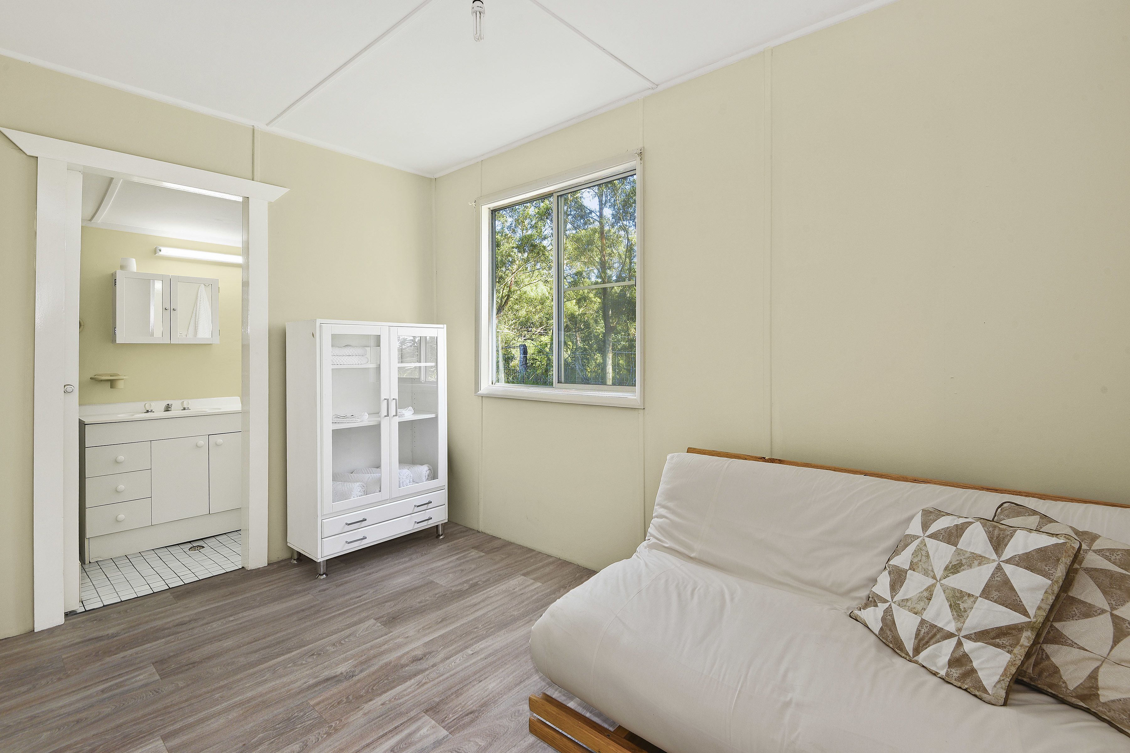 A bedroom with a bed, a wardrobe, a cabinet, and a window with a view of trees.