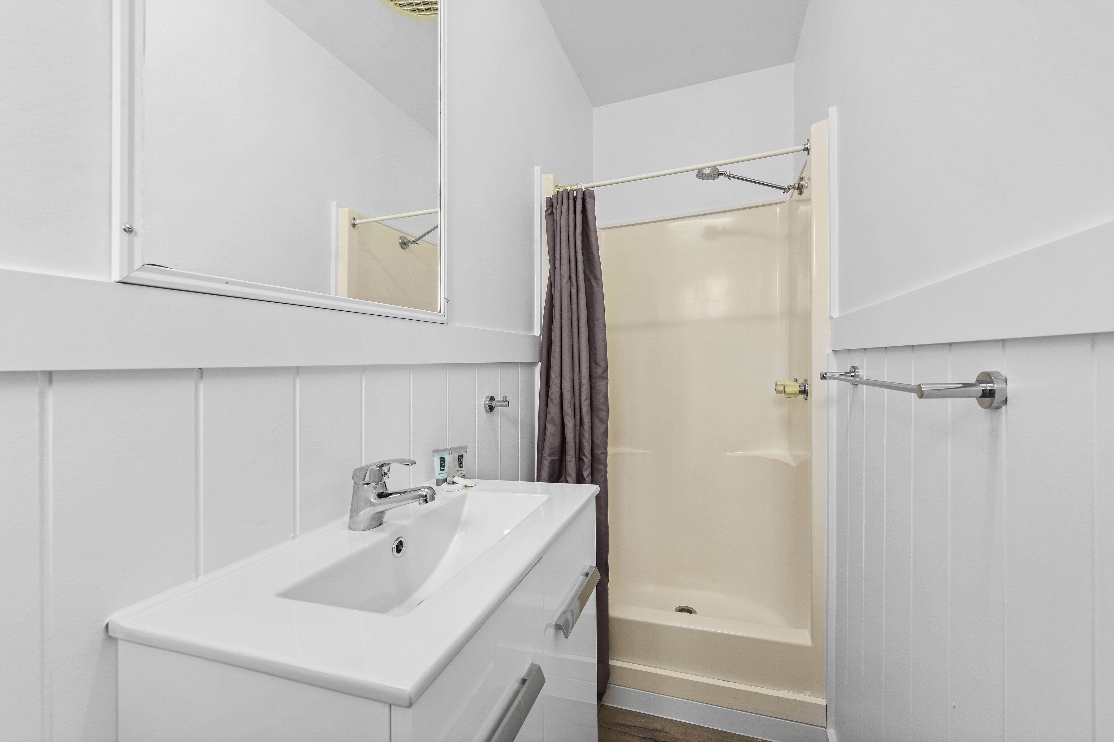 A bathroom with a white sink, a mirror, and a shower with a curtain.