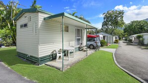 A single-story mobile home with a green roof, a covered porch, and a small patio area with a table and chairs. - Diamond Waters Caravan Park (Dunbogan)