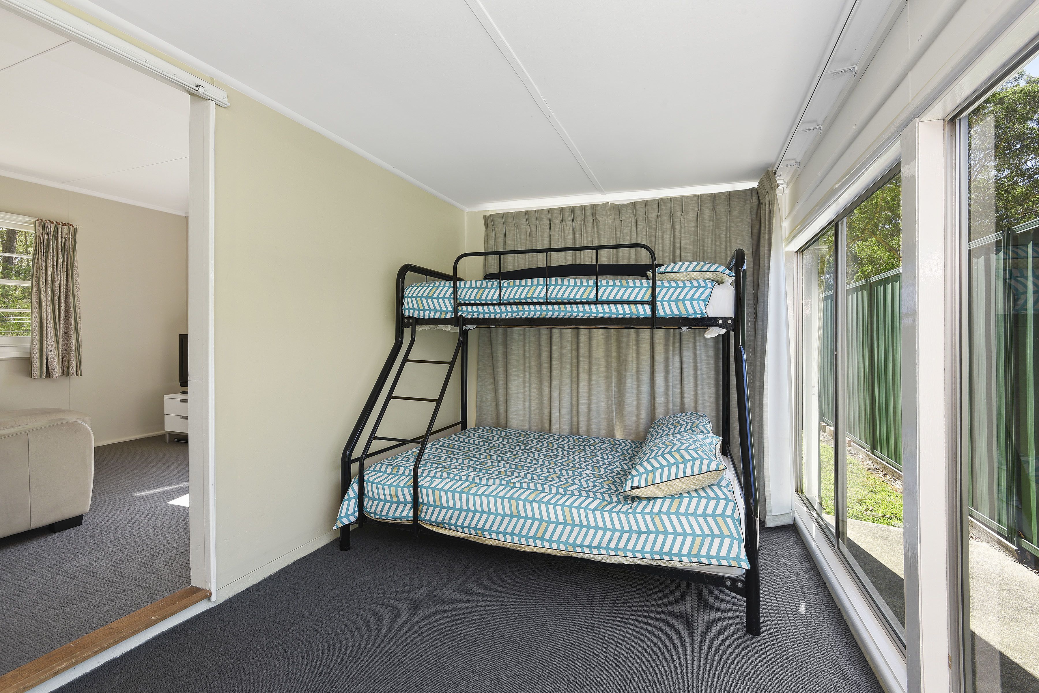 A bunk bed room with a window, a desk, and a chair.