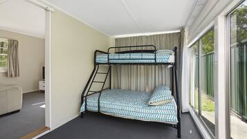 A bunk bed room with a window, a desk, and a chair.