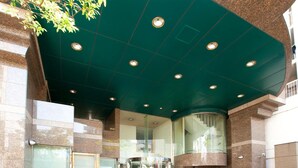 A modern building entrance with a glass revolving door, a green ceiling, and a stone facade. - Pearlhotel Kawasaki (Kawasaki)