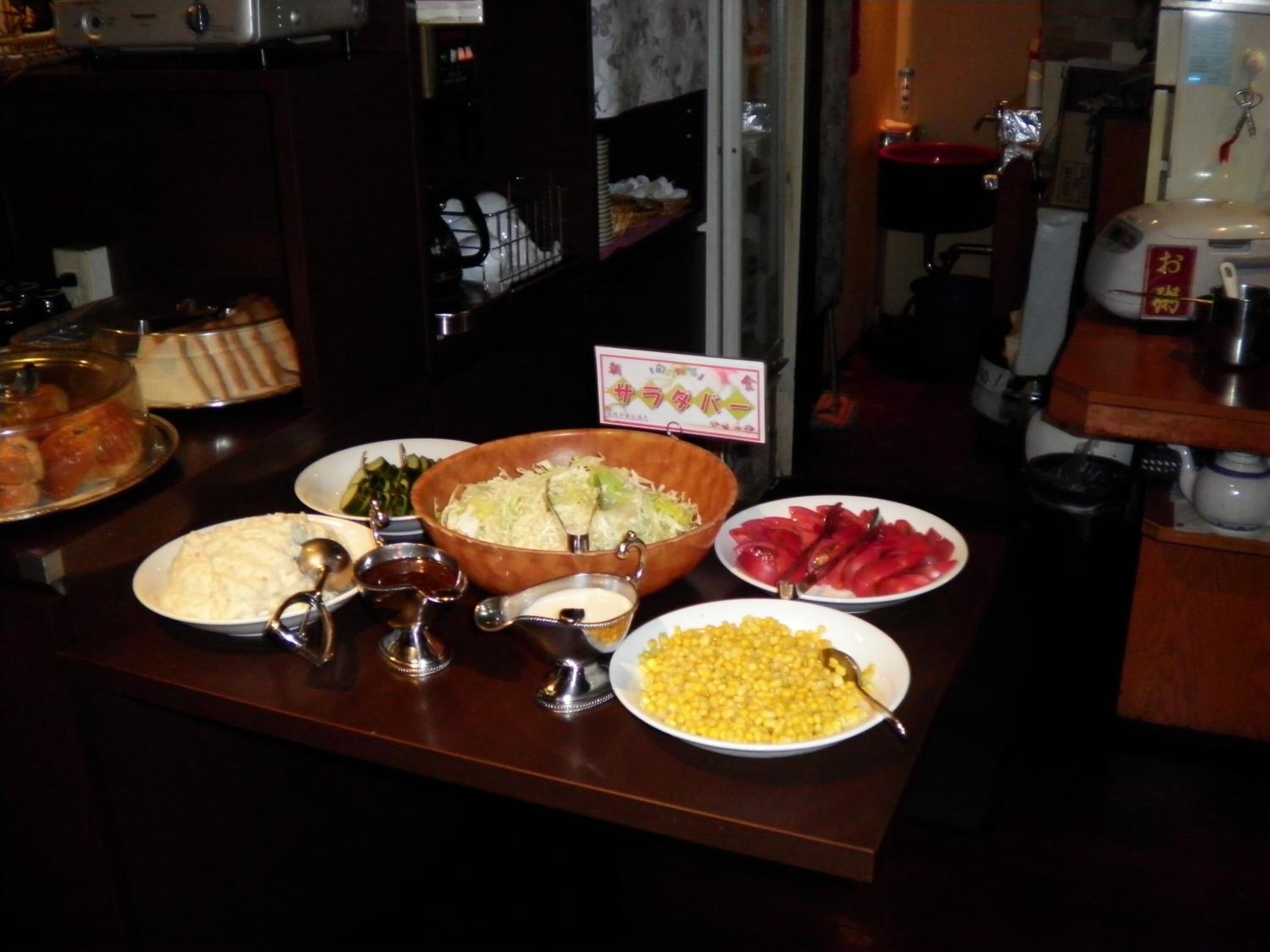 A buffet table with various dishes including a large bowl of cabbage, a plate of corn, and a dish of red vegetables.