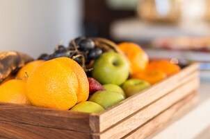A wooden crate filled with various fruits including oranges, apples, and grapes.