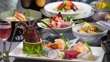 A variety of dishes including seafood and vegetables, arranged on a table with a glass of red wine.