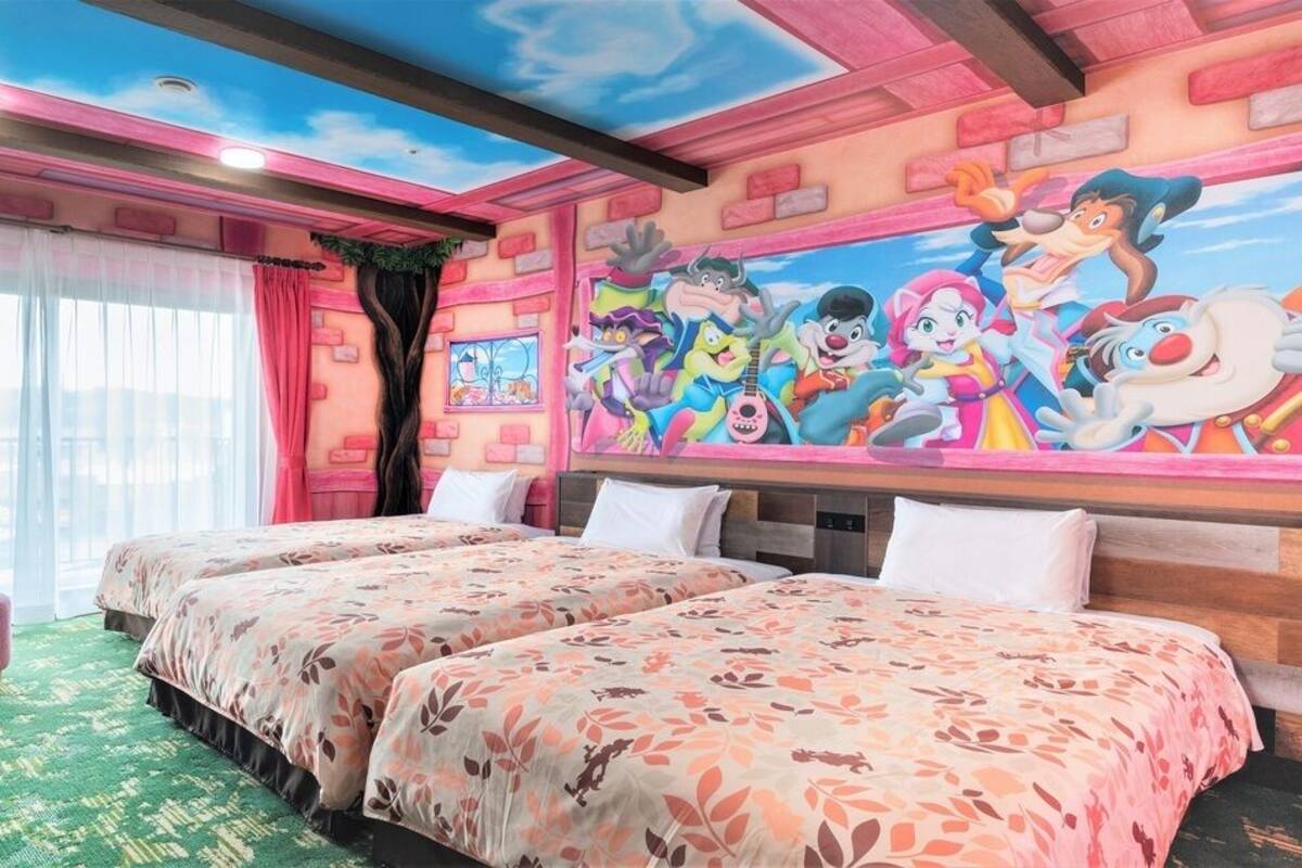 Een hotelkamer met twee bedden, een eettafel en een muurschildering.