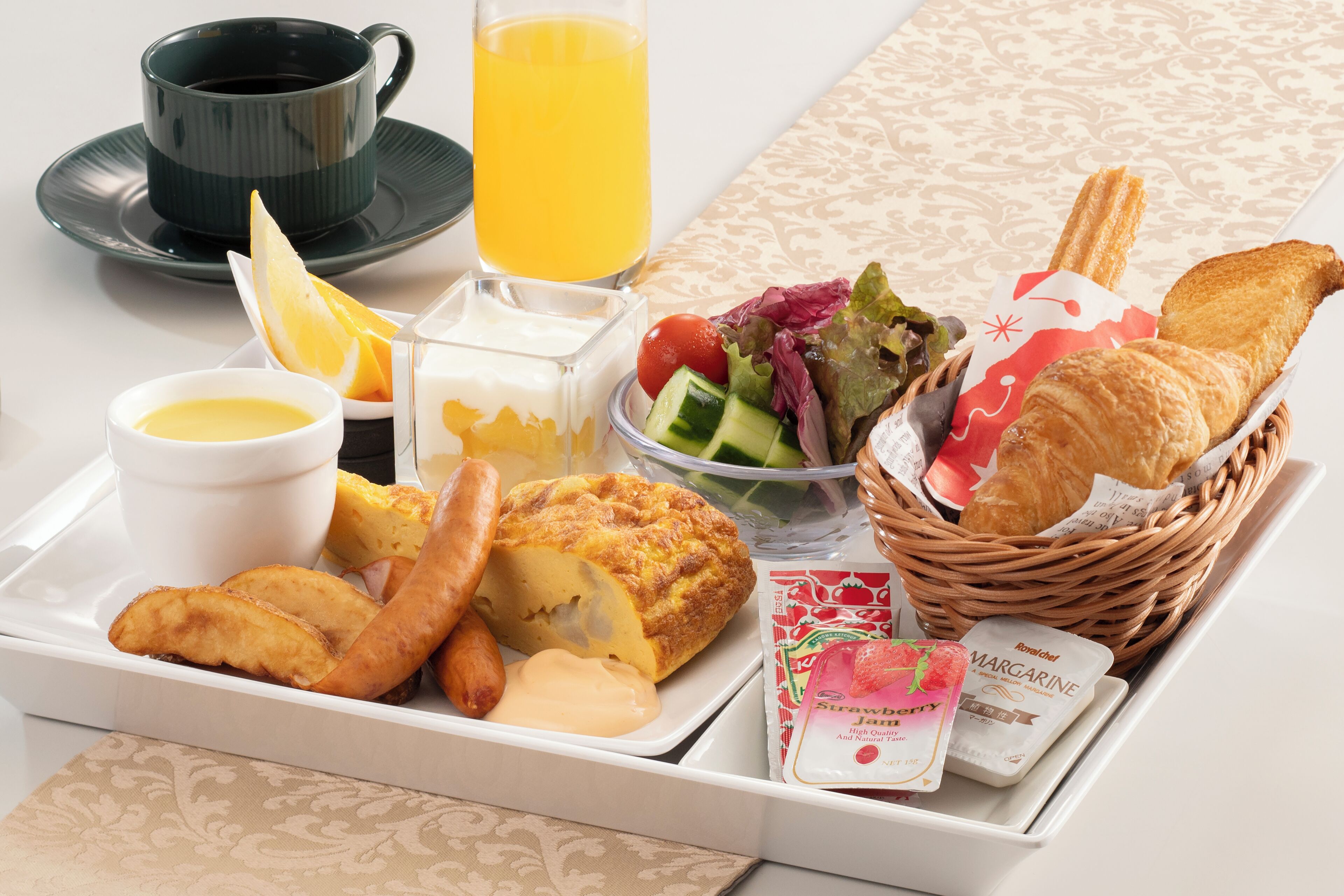 Ein Tablett mit Frühstücksangeboten, darunter Toast, Eier, ein Salat und Saft.