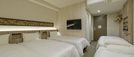 A hotel room with two beds, a TV, a wardrobe, and an air conditioning unit.
