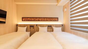 A hotel room with two beds, a flat-screen TV mounted on the wall, and a wooden headboard with a decorative panel above.