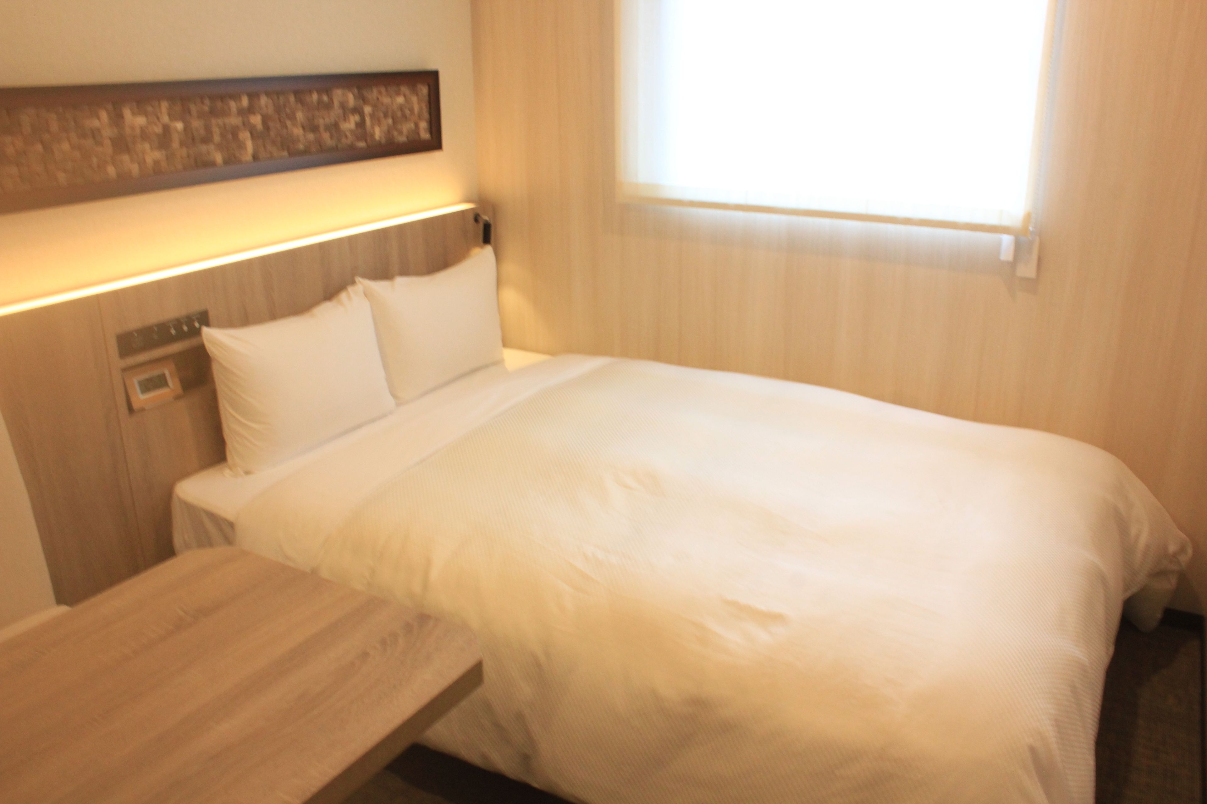 Ein Hotelzimmer mit Bett, Nachttisch und einer kleinen Holzbank.