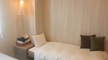 Habitación de hotel con cama, mesita de noche, lámpara y repisa con artículos de aseo.