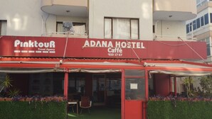 Um hostel chamado 'ADANA HOSTEL' com uma agência de viagens 'Pinktour' à esquerda.