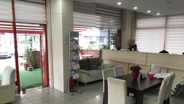 Um restaurante com área de refeiç ões, incluindo uma mesa, cadeiras, um sofá e um extintor de incêndio.