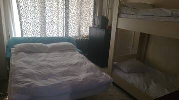 Habitación con literas, una cama individual y un televisor sobre un mueble.
