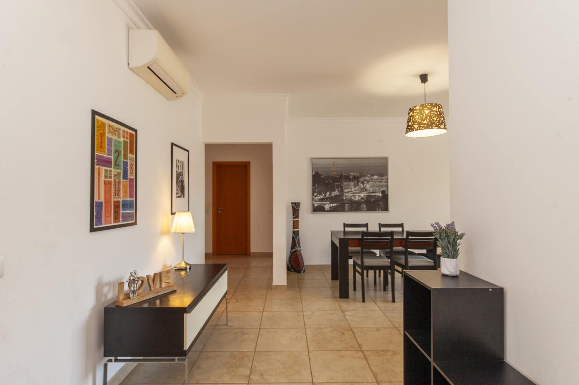 A modern kitchen with a black countertop, a wooden cabinet, and a dining area with a table and chairs.