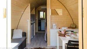 Un interior acogedor de madera con techo curvo, una kitchenette, comedor y zona de estar.