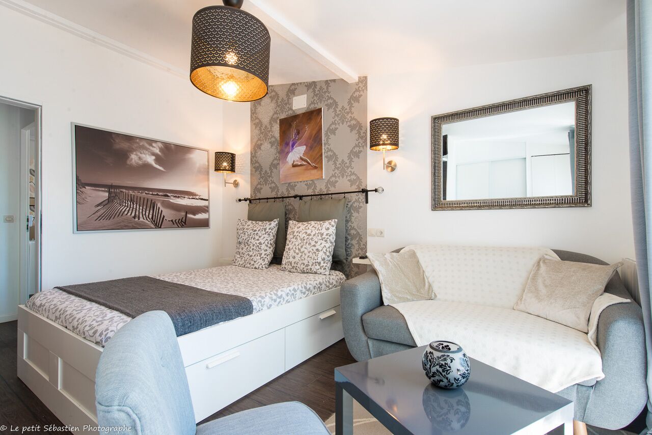 Un dormitorio moderno con una cama, un sofá, una mesa y lámparas fijadas a la pared.
