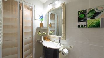 A bathroom with a glass shower enclosure, a sink with a mirror, and a toilet.