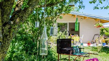 A rustic outdoor setting with a metal cart, hanging glass bottles, and a tree.