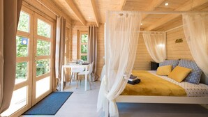 Un dormitorio de cabaña de madera con cama, escritorio y ventana.