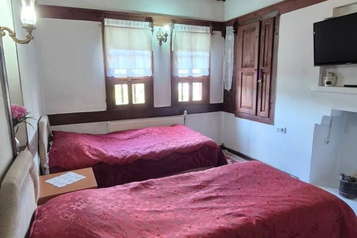 Een kamer met twee bedden, een houten plafond, een flatscreen televisie en een raam met gordijnen.